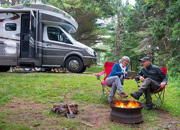 A couple enjoying a fire pit outside their RV